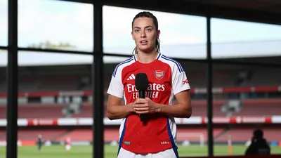 A dynamic medium shot of an Arsenal Women midfielder in her late 20s, dressed in the club's home kit of red shirt with...