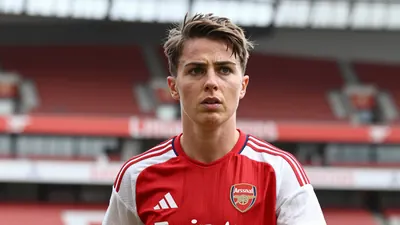 A determined 28-year-old Arsenal Women midfielder, with short brown hair and focused eyes, wears the red and white home...