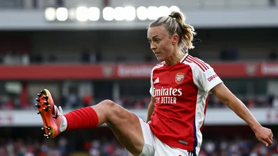 A young Arsenal Women player in a red and white kit, mid-kick during a WSL match